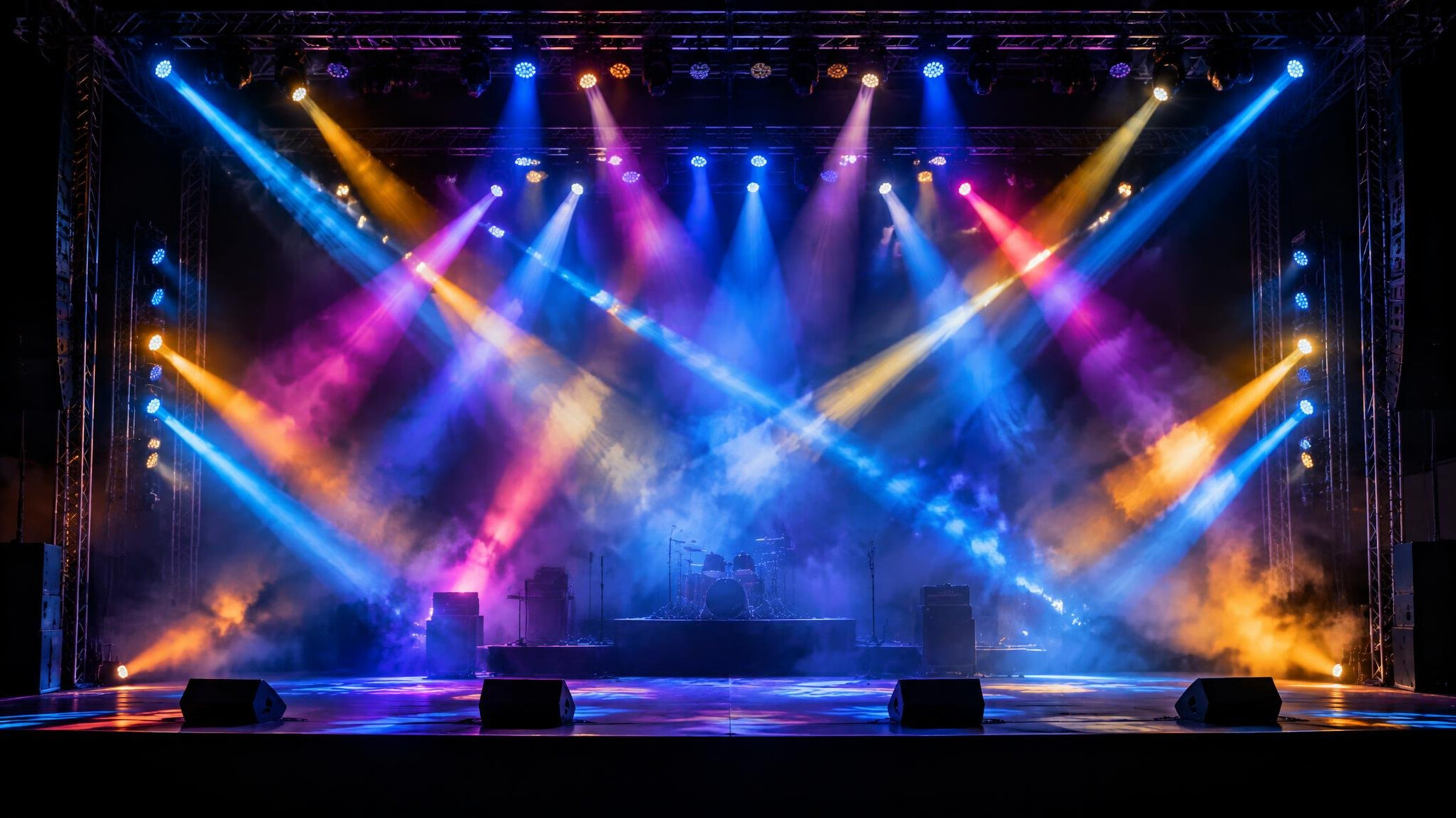 Stage lighting rig with colorful beams crossing an empty concert stage