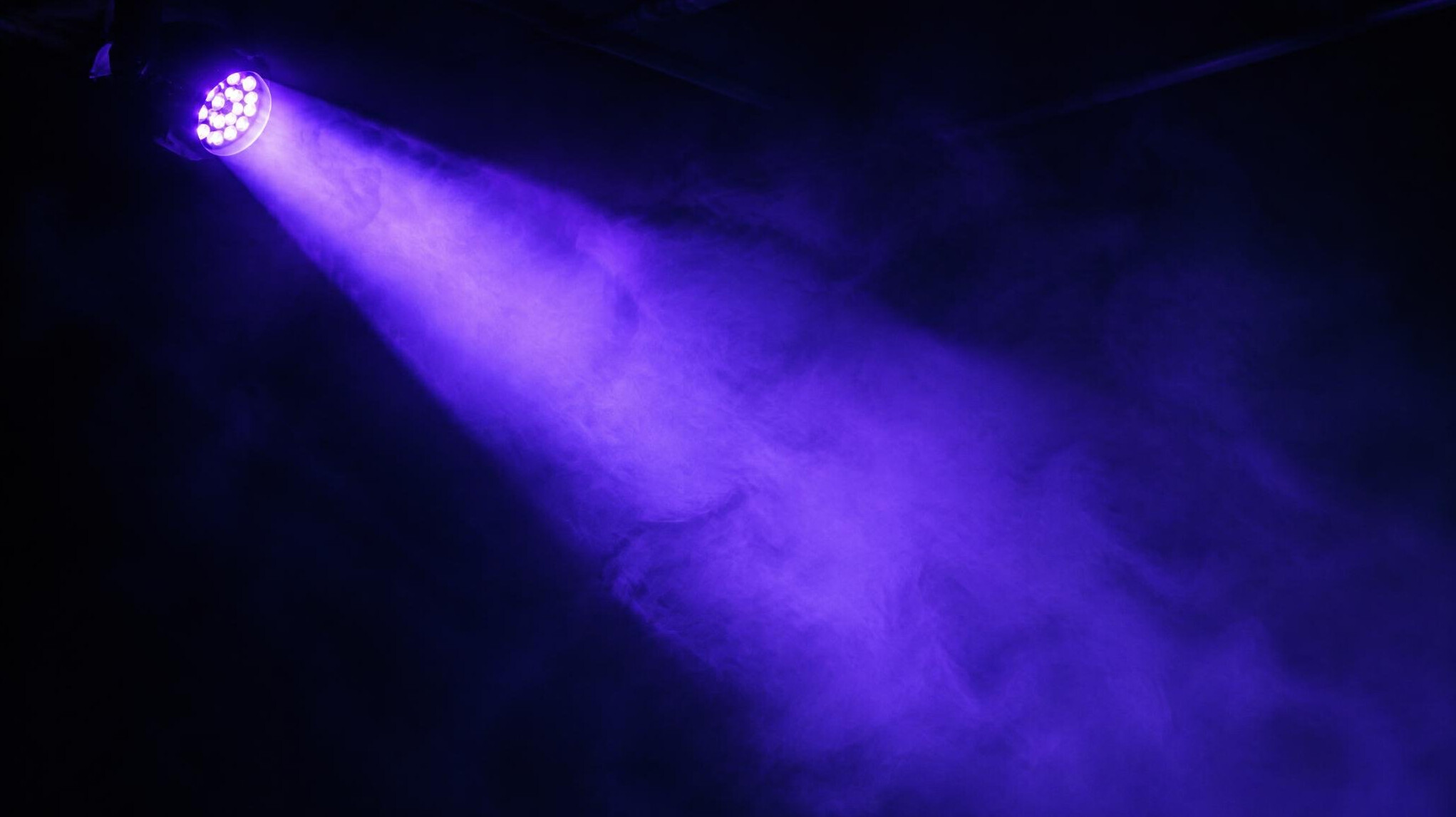 Close-up of a colored stage light beam cutting through darkness